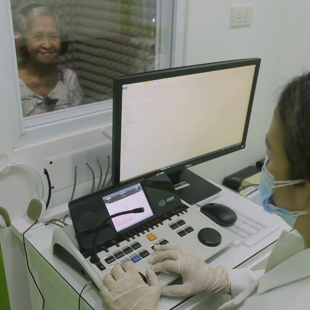 Grandmother inside hearing test booth for assessment
