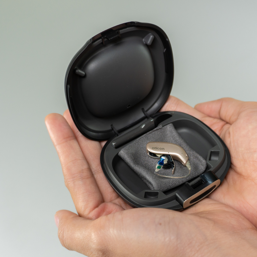 Oticon hearing aid with case placed on top of hands